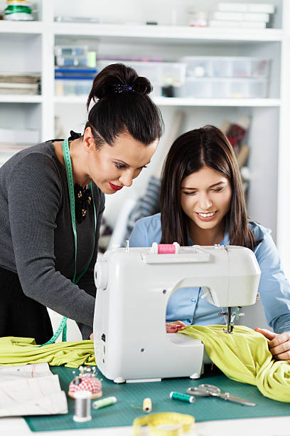 A student learning to use a modern sewing machine in a bright workshop